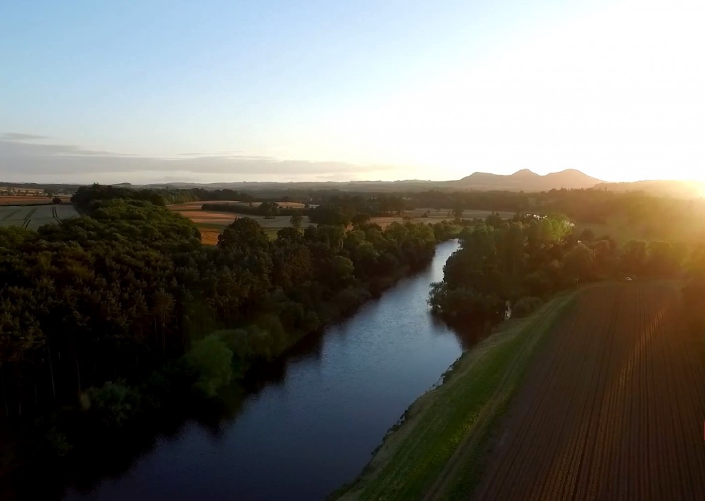 The River Tweed winding through Borders farmland at sunset with the Eildon Hills beyond